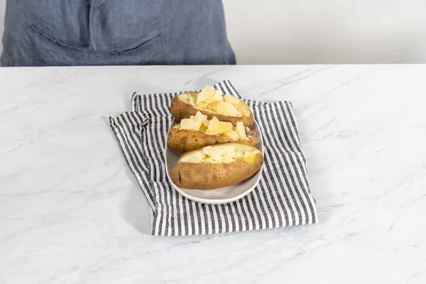 Pressure Cooker Baked Potatoes. Sliced cooked whole potatoes on a white plate to make baked potatoes.