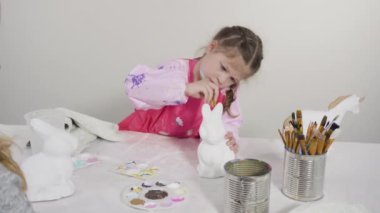 Küçük kız evde eğitim projesi için akrilik boyayla heykelcikler boyuyor..