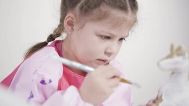 小さな女の子の絵画紙は彼女のホームスクーリングアートプロジェクトのためのアクリル塗料で人形をマッシュ — ストック動画