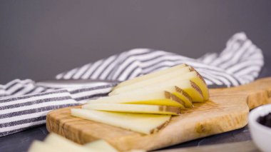 Ağaç kesme tahtasındaki küçük dilimlere peyniri dilimleyen gurme..