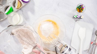 Düz yatıyordu. Adım adım. Vanilyalı Mardi Gras kekleri pişirmek için karışımı elektrikli mikserle karıştırıyorum..