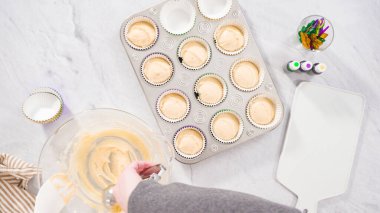 Düz yatıyordu. Adım adım. Vanilyalı Mardi Gras keki pişirmek için kek hamurunu folyoya batırıyorum..