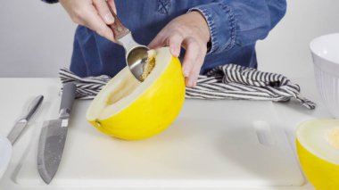 Adım adım. Beyaz kesme tahtasında kaygan altın çiğ taneli kavun.