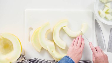 Adım adım. Düz yatıyordu. Beyaz kesme tahtasında kaygan altın çiğ taneli kavun.