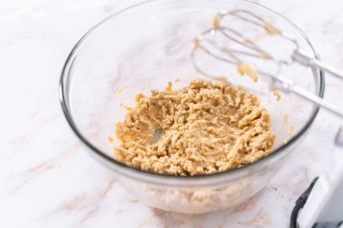 Elmalı yulaflı kurabiye pişirmek için büyük bir bardakta karıştırma malzemesi..