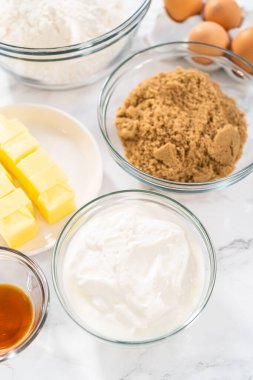 Bardaktaki ölçülü malzemeler karıştırma kaseleri kırmızı kadife kekler ve beyaz çikolatalı ganache kreması..