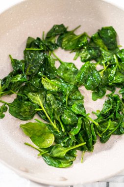 Ispanaklı sarımsaklı karides makarna hazırlamak için önemsiz bir tavada taze ıspanak kızartıyorum..