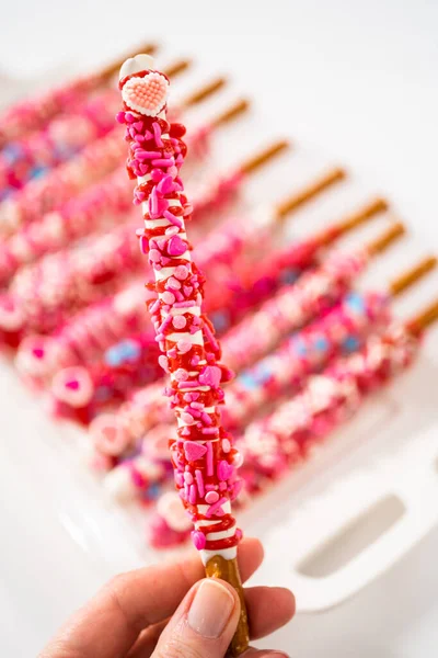 バレンタインデーにハート型のスプリンクルで装飾されたチョコレートで覆われたプレッツェルロッド — ストック写真