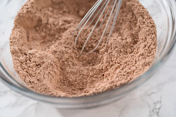 Büyük bir bardakta ıslak malzemeler karıştırarak kırmızı kadife kekler ve beyaz çikolatalı ganache kreması pişiriyorum..