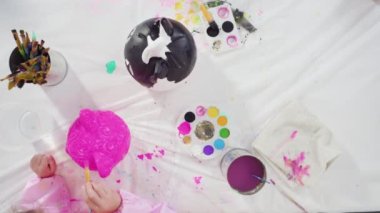 Cadılar Bayramı için akrilik boyayla balkabağı boyayan küçük kız..