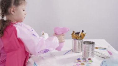Küçük kız evde eğitim projesi için akrilik boyayla heykelcikler boyuyor..