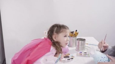 Küçük kız evde eğitim projesi için akrilik boyayla heykelcikler boyuyor..