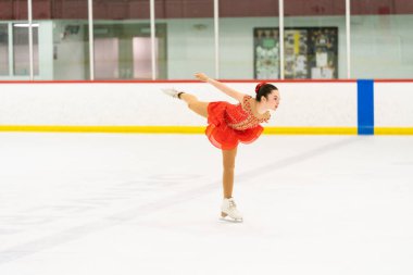 Genç kız buz pateni pistinde artistik patinaj yapıyor..