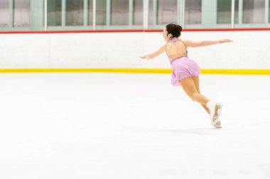 Genç kız buz pateni pistinde artistik patinaj yapıyor..