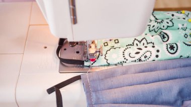 Koronavirüs salgını için dikiş makinesiyle pamuk yüz maskesi dikiyorum..