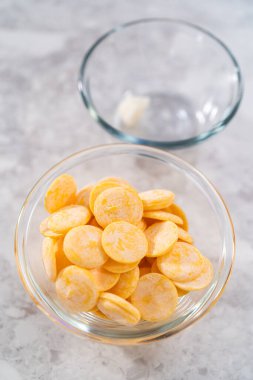 Mutfak tezgahındaki küçük cam kasede sarı çikolata parçaları..