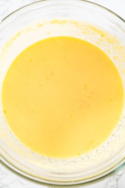 Küçük Paskalya ekmeği pişirmek için ıslak malzemeleri büyük bir bardakta karıştırıyorum..