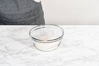 Mixing dry ingredients with a hand whisk in a large glass mixing bowl to bake lemon cupcakes.