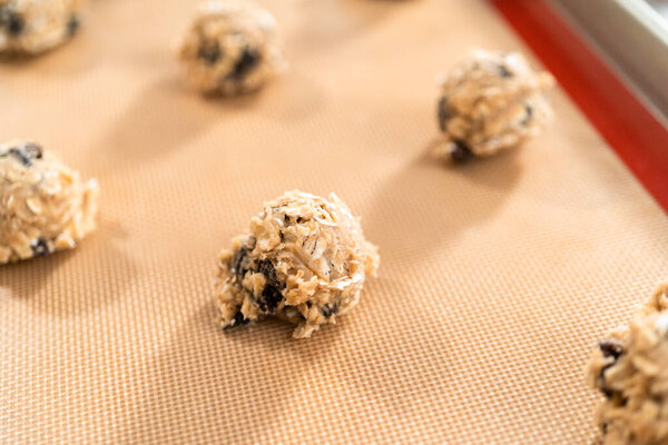 Scoops of cookie dough on a baking cheets to bake chewy oatmeal raisin cookies.