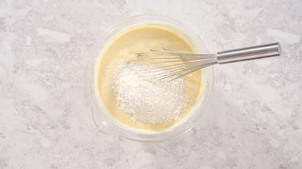 Flat lay. Step by step. Mixing ingredients in a glass mixing bowl to prepare coconut banana pancakes.