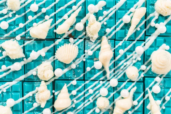 Mini mermaid chocolate bars drizzled with white chocolate, sprinkling with white pearl sugar sprinkles, and decorated with a white chocolate seashells.