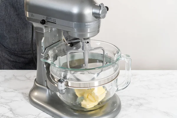 Mixing ingredients in kitchen electric mixer to make lemon buttercream frosting.