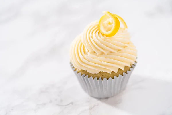Lemon cupcakes with lemon buttercream frosting, and decorated with lemon swist.
