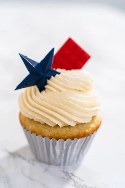 Lemon cupcakes with lemon buttercream frosting, and decorated with patriotic blue chocolate star and red mini chocolate.