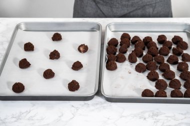 Naneli beyaz çikolatalı kurabiyeler pişirmek için parşömen kağıdıyla kaplı küçük bir hamur kepçesiyle kurabiye hamuru pişirmek..