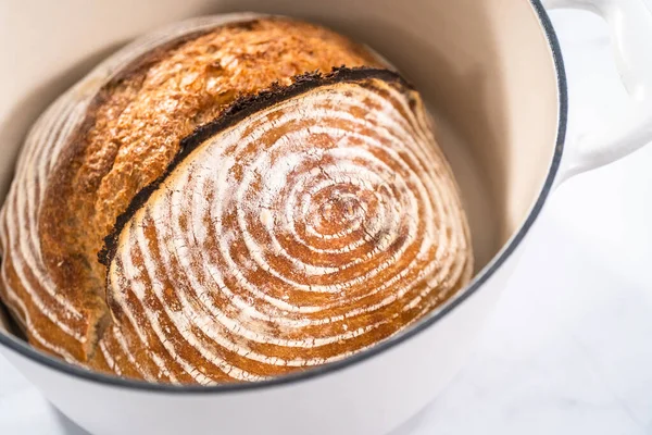 焼きたての小麦のパン生地のパンに エナメル鋳鉄製のオランダのオーブンでパンの防水バスケットのマークが付いています — ストック写真