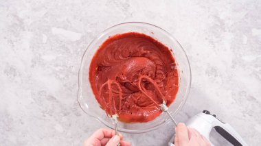 Düz yatıyordu. Adım adım. Kırmızı kadife kek hazırlamak için karıştırma kabındaki malzemeleri karıştırıyorum..