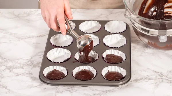 Step by step. Baking chocolate cupcakes. Scooping chocolate cupcake batter into a cupcake pan.