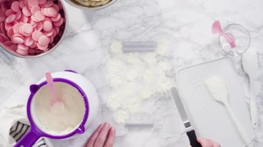 Düz yatıyordu. Adım adım. Erimiş çikolatayı kar taneleri şeklinde plastik bir çikolata kalıbına döküyorum..