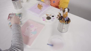 Uzak bir sanat projesi için annesiyle tuvale akrilik boyayla resim yapan küçük bir kız..