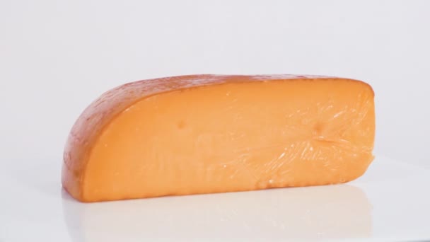 Große Scheibe Geräucherter Gouda Käse Auf Weißem Hintergrund — Stockvideo