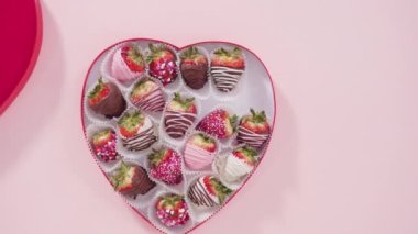 Flat lay. Step by step. Arranging a variety of chocolate dipped strawberries in a heart shaped gift box on pink background.