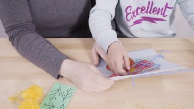 Küçük kız annesiyle el sanatları masasında dikiş dikmeyi öğreniyor..