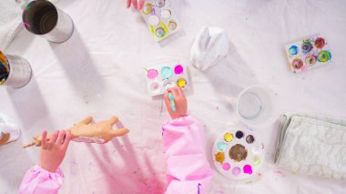 Düz yatıyordu. Evde resim dersinde kağıt heykel boyayan küçük bir kız..