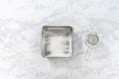 Flat lay. Greasing metal square baking pan to bake sweets.