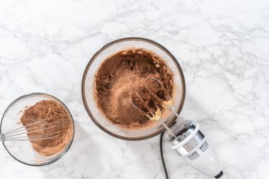 Flat lay. Mixing ingredients with a hand mixer to bake chocolate cookies with chocolate hearts for Valentines Day.