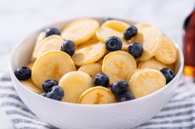 Taze yapılmış mini krep gevreği ve beyaz kasede taze yaban mersini..