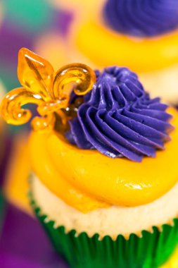 Mardi Gras vanilyalı kekler folyo kaplarda ve İtalyan tereyağlı kremayla süslenmiş..