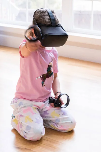 Little girl playing virtual reality game in the living room,