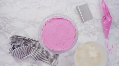 Time lapse. Flat lay. Step by step. Frosting round funfetti cake with white italian buttercream frosting.