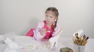 Evde resim dersinde kağıt heykel boyayan küçük bir kız..