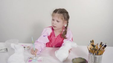 Evde resim dersinde kağıt heykel boyayan küçük bir kız..