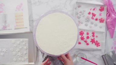 Düz yatıyordu. Adım adım. Yuvarlak funfetti pastasını pembe ve beyaz fondant kar taneleriyle süslüyorum..