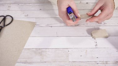 Adım adım. Kahverengi kağıttan hediye etiketlerini kağıt punçla kesiyor..