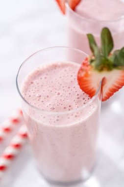 Taze taze çilek ve kağıt kamışla süslenmiş sağlıklı bir kahvaltı muzlu smoothie..