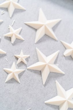 Filling silicone mold with white melted chocolate to make chocolate chocolate stars for American flag mini cupcakes.
